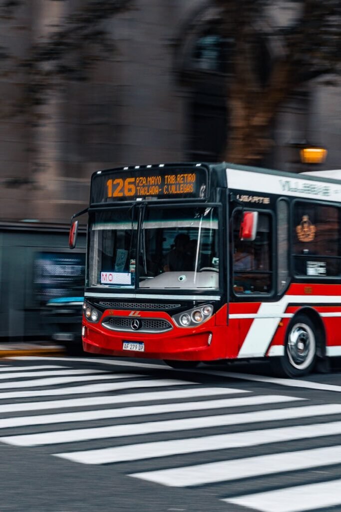 Dynamic capture of a red city bus crossing a street in an urban setting.