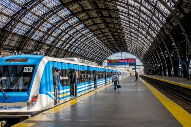 Faceless passengers and train driver at modern train station under arched roof