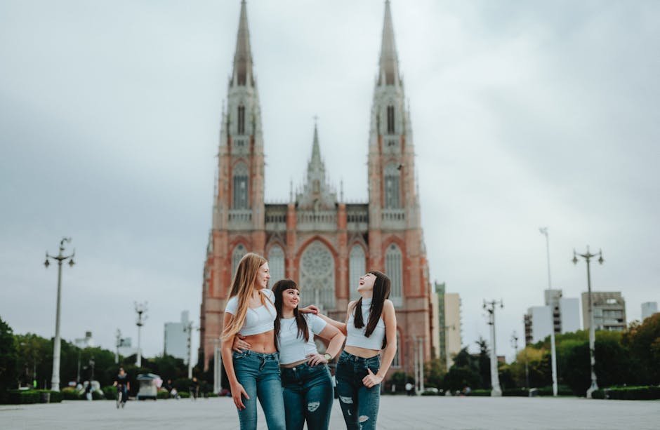 Three women share a joyful moment in front of the iconic La Plata Cathedral, Argentina.