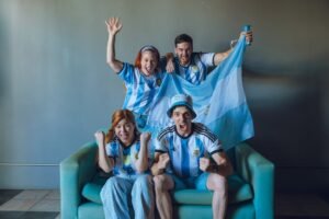 Group of fans celebrating Argentina's soccer victory at home, wearing team jerseys.