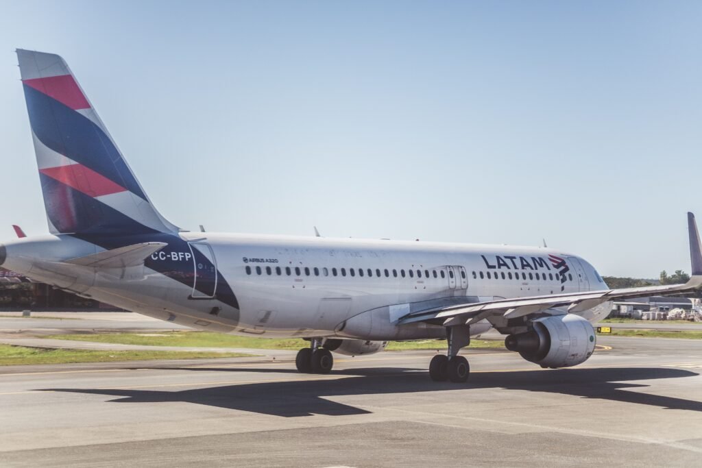 A LATAM Airlines Airbus A320 preparing for takeoff on a sunny airport runway.